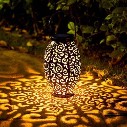 A solar lamp glows to create patterns on an outdoor patio at night