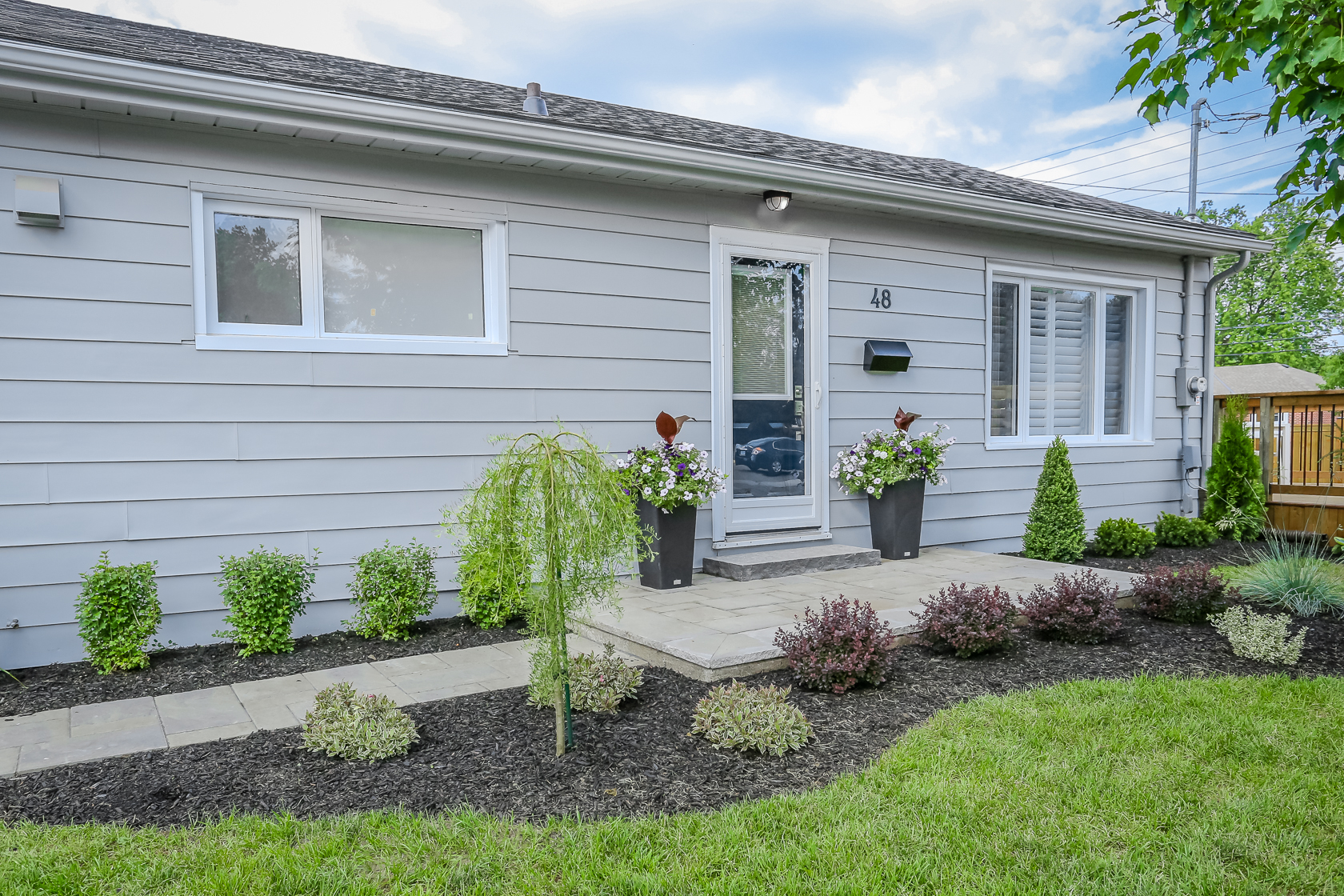 Home with grey siding and bushes and planters