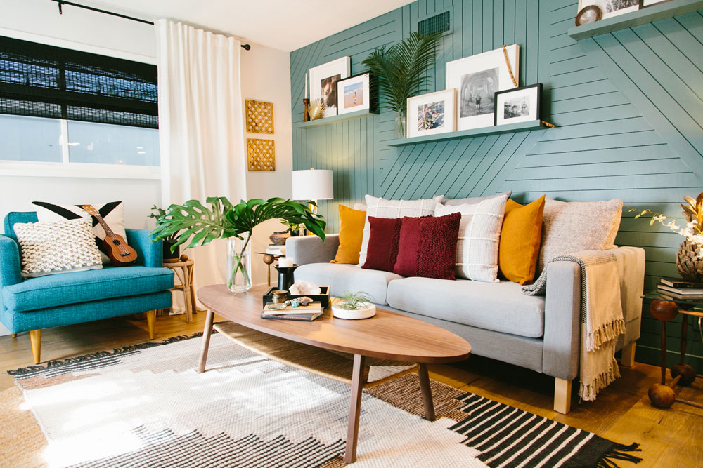 Deep aqua accent wall with a ridged treatment in a retro living room with funky carpets, jewel-tone pillows, mid-century modern furniture as featured on HGTV’s Hidden Potential