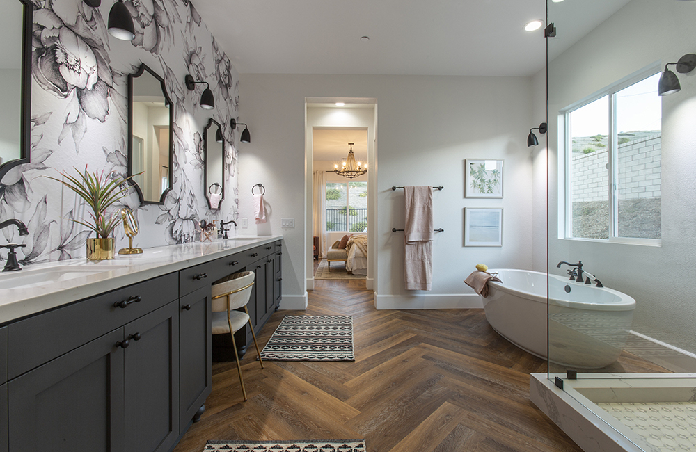 Beautiful bathroom featuring a wood herringbone floor, large white oval bathtub long white countertop vanity, a wallpaper feature wall as seen on Rock the Block on HGTV Canada
