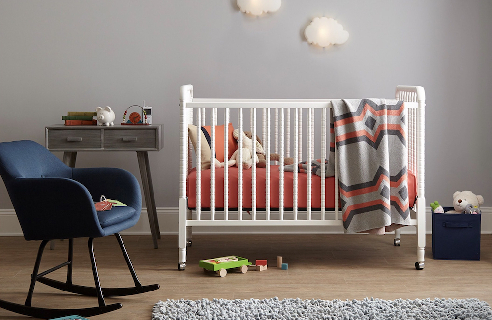 Modern nursery with white crib paint in BEHR White Veil OR-W14, a navy blue rocking chair, and walls painted in BEHR Rock Crystal MQ3-28