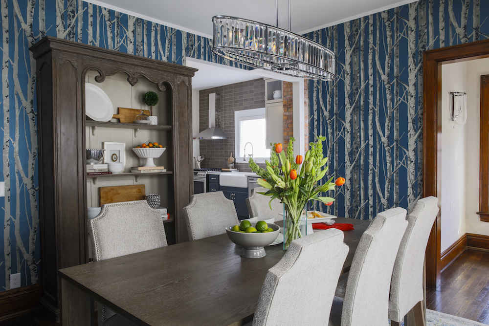 Renovated history dining room with birch-patterned wallpaper and rustic wood furniture.