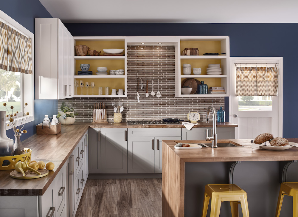 Modern kitchen with navy blue walls, a brown tile backsplash, and a wooden island with yellow benches