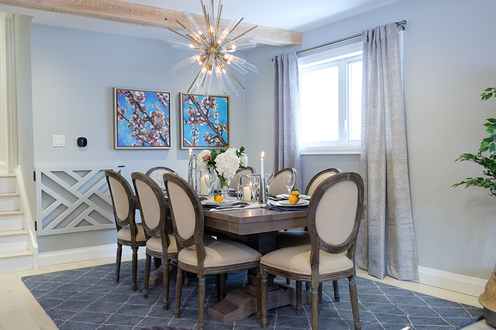 Chic dining room with a blue area rug, silver drapes and a starburst chandelier