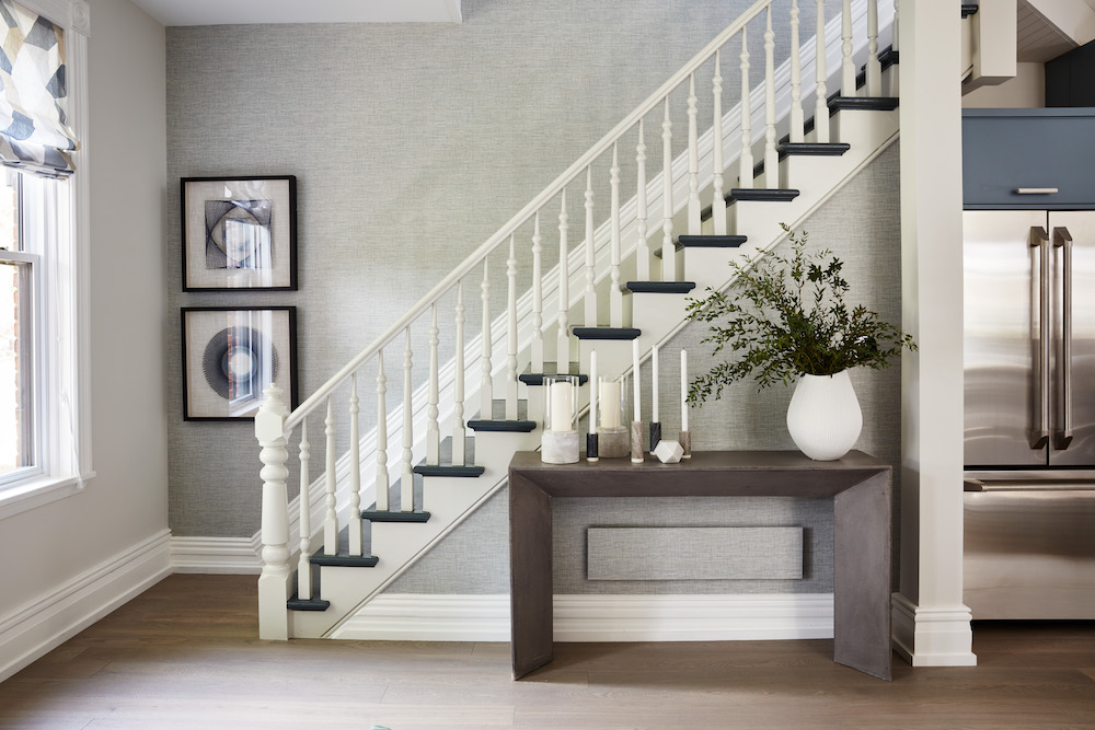 Beautiful stairwell with grey textured wallpaper, white railing and blue steps leading to second story