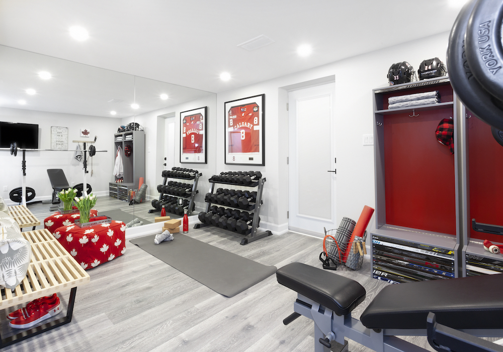 A basement home gym with grey floors, red accents and a rack of dumbbells