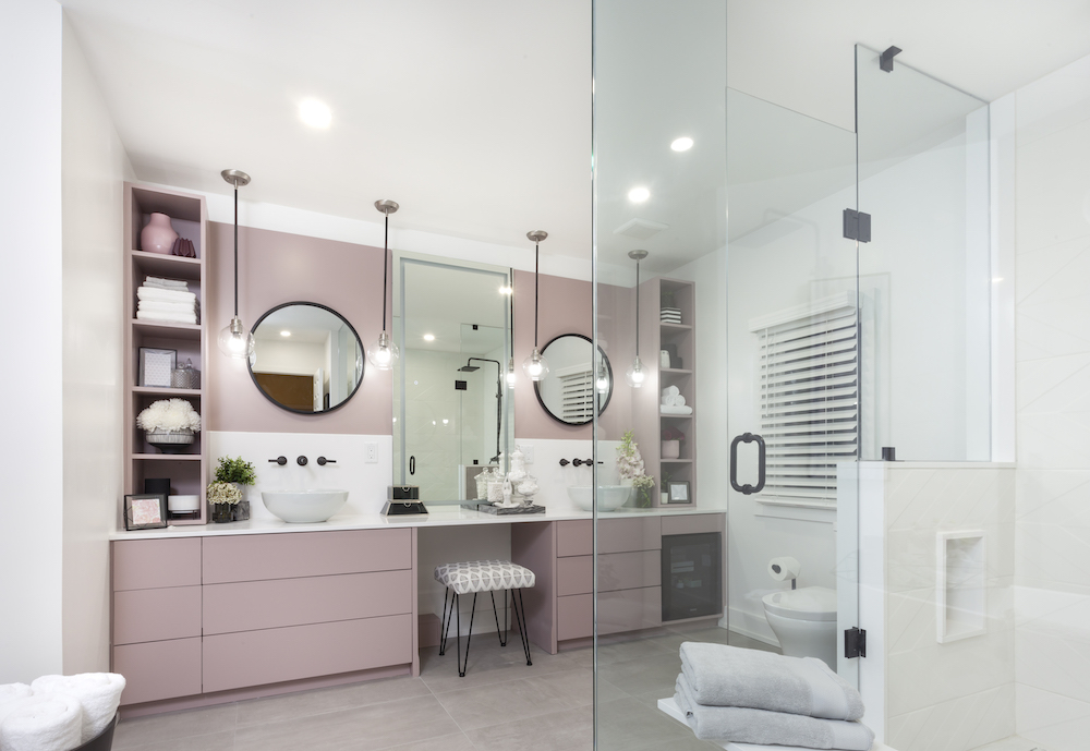 Modern bathroom with dusty rose cabinets, grey tiled floors and two round mirrors