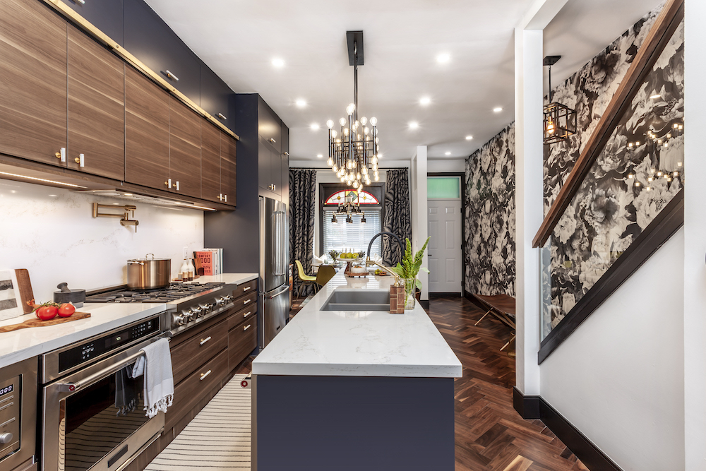Modern kitchen with a navy blue island, wooden cabinets and herringbone dark wood floor