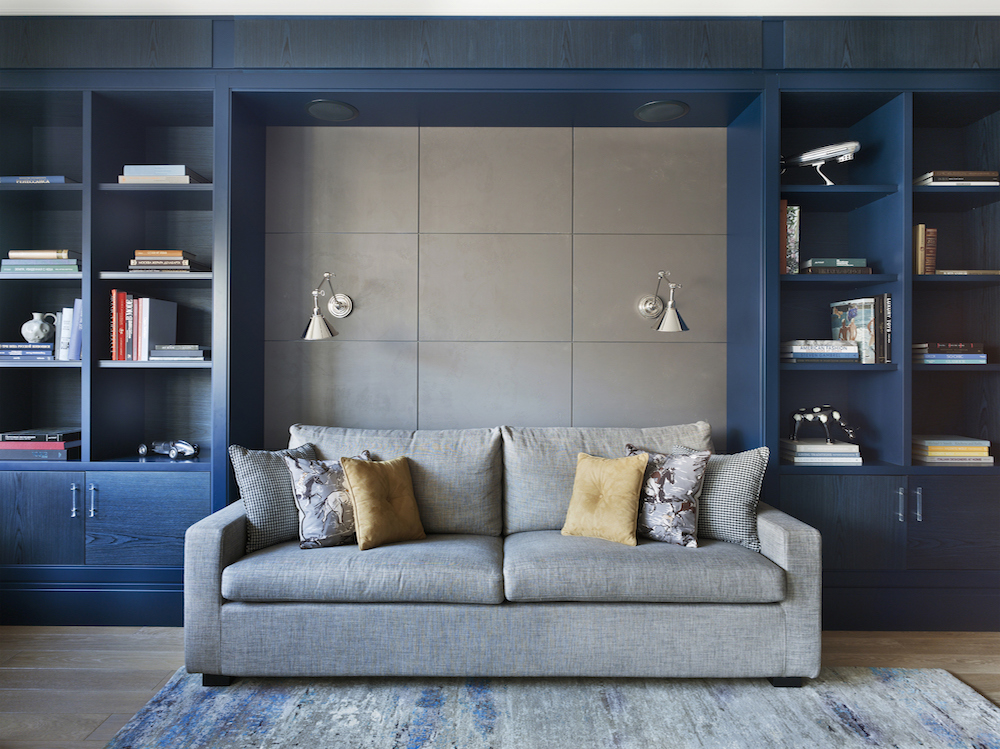 Seating area in living room in apartment with grey couch and blue shelves