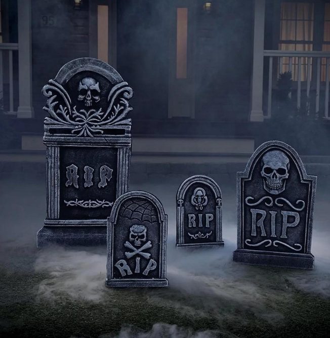 Four plastic tombstones for Halloween decor in a front yard