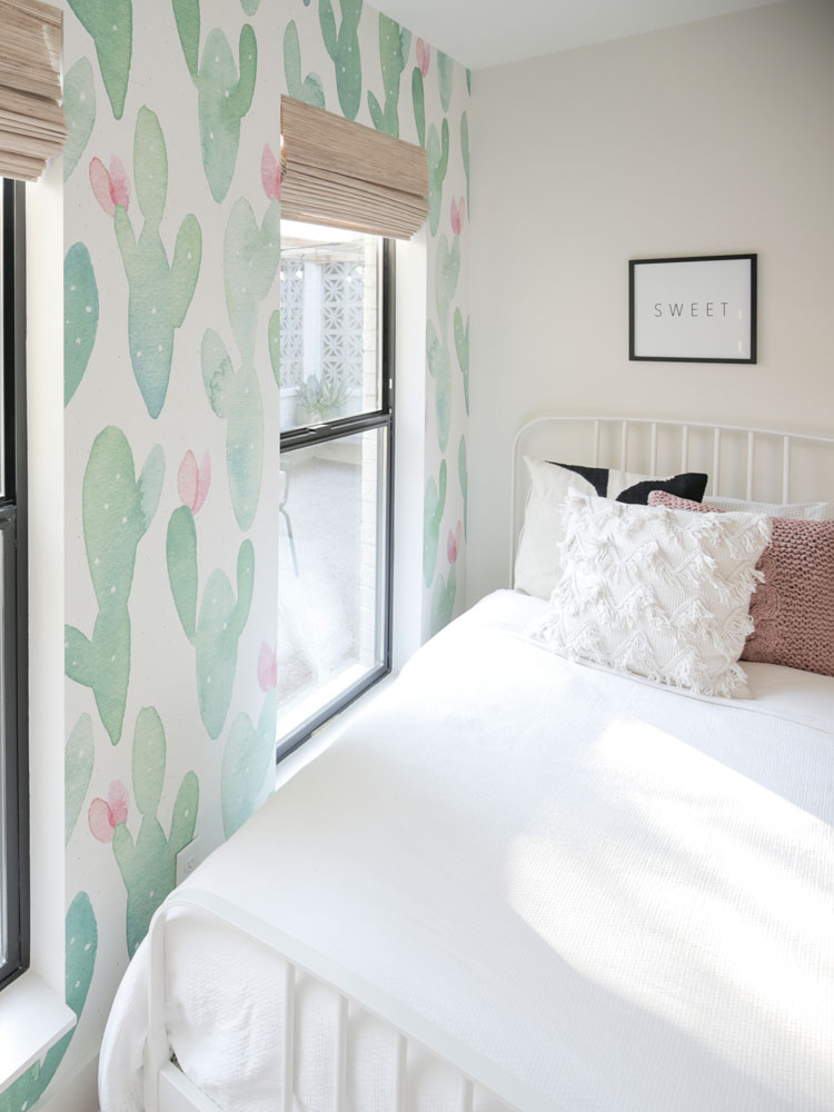 Girl's bedroom with cactus wallpaper, roman blinds and simple white bedding.