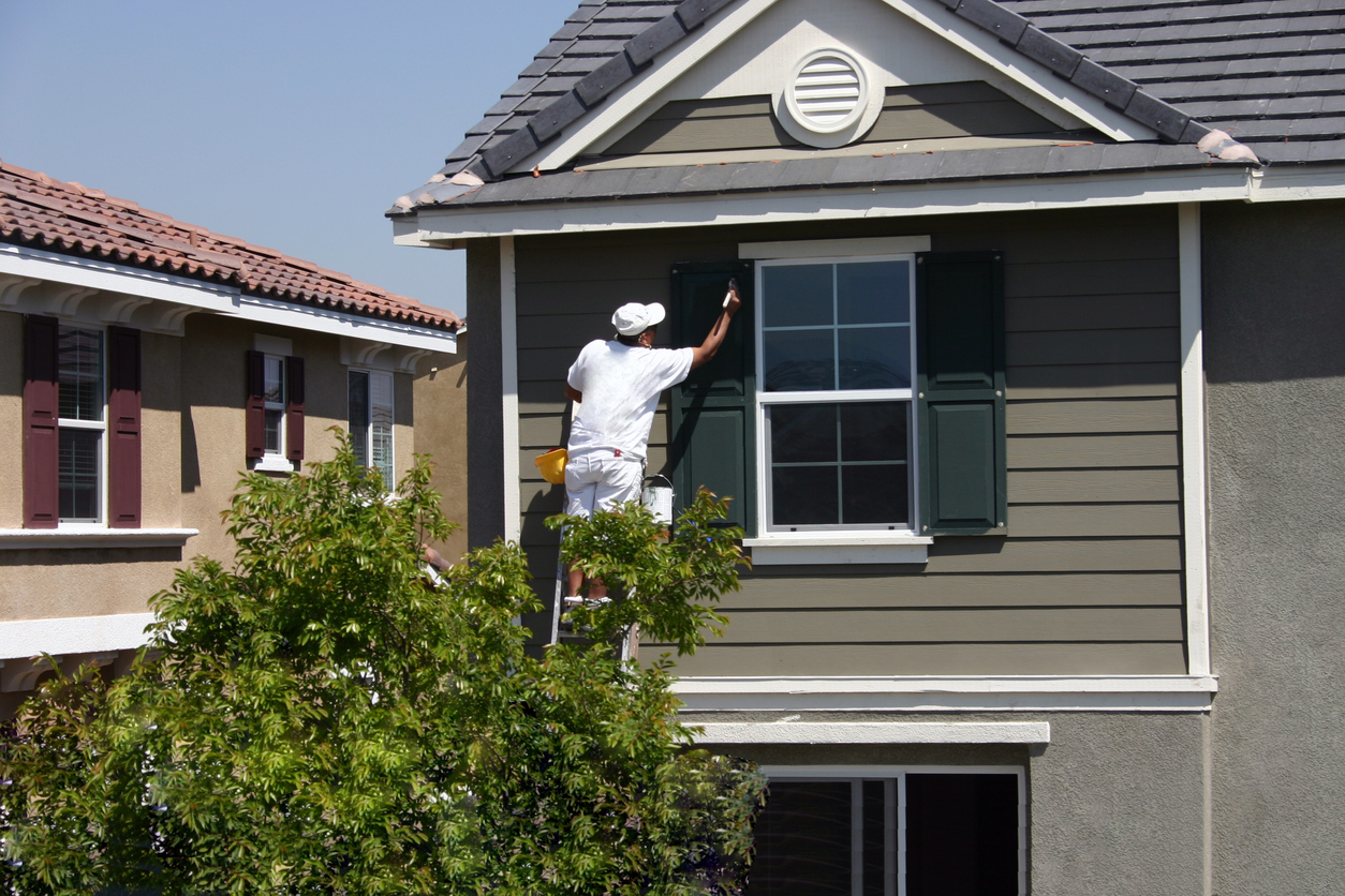 Man painting siding of home
