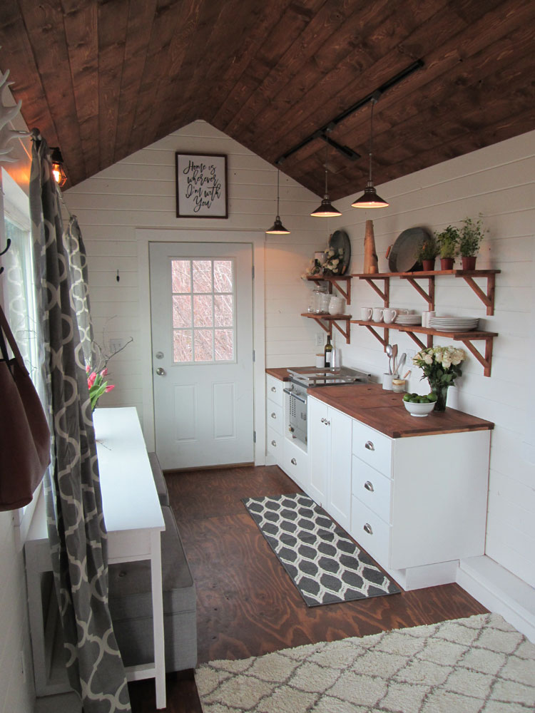 Cottage kitchen with rustic shelves, plants, pendants and happy artwork.