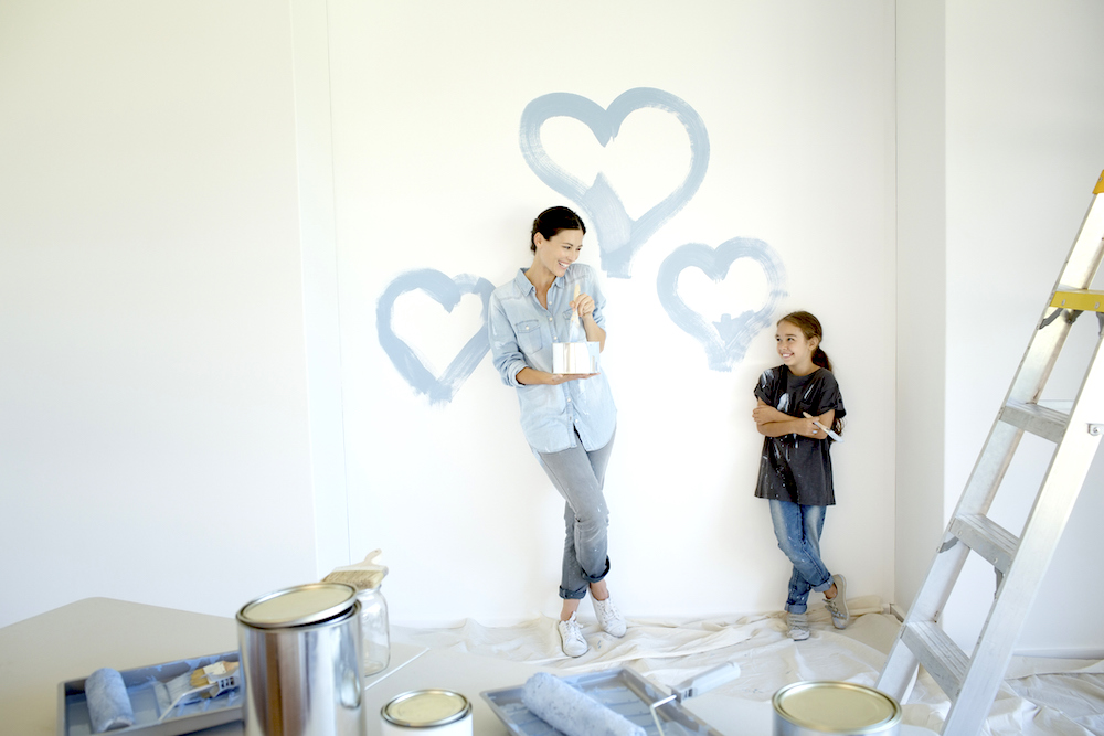 Mother and daughter painting blue hearts on wall