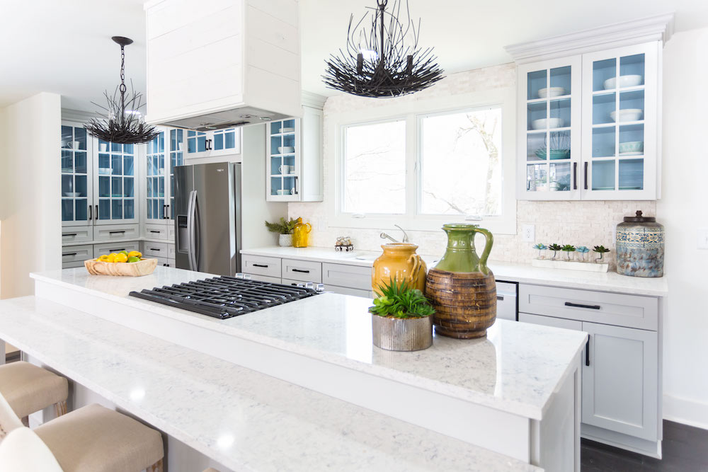 Masters of Flip split level kitchen island quartz countertop with bird’s nest chandeliers and white cabinets with blue interior