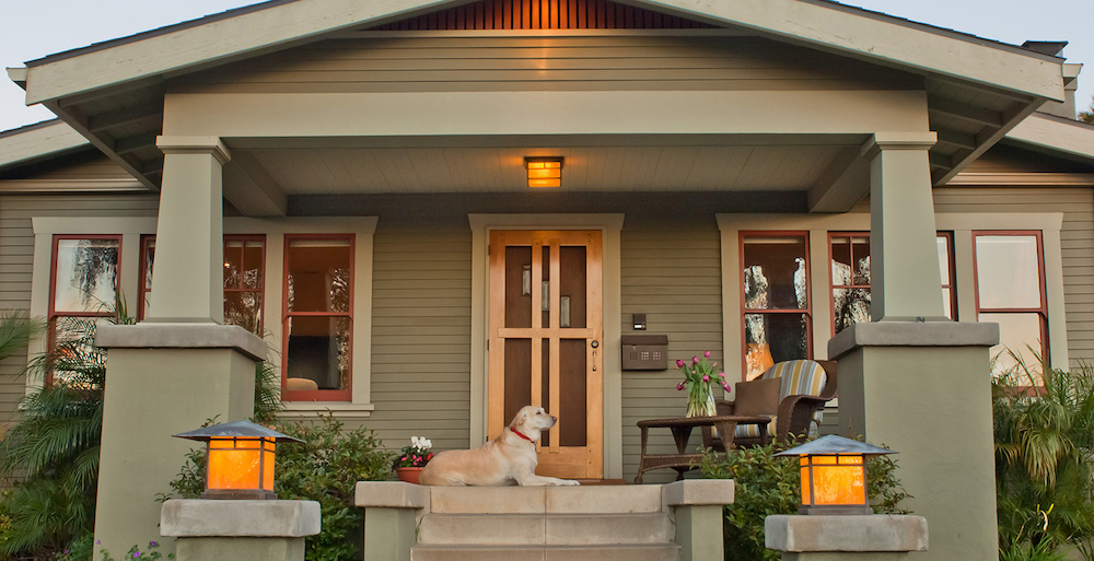 green-grey craftsman home with dog on front porch