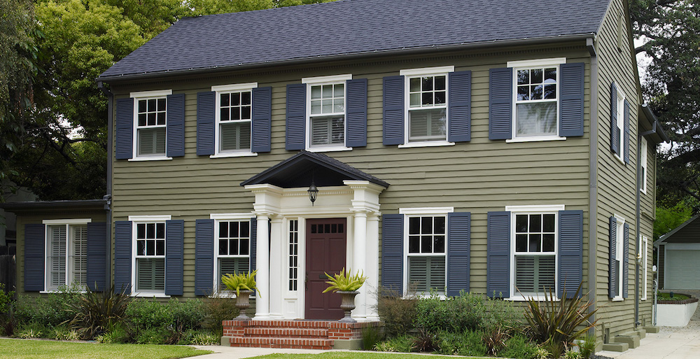 green colonial-style house with navy window shutters