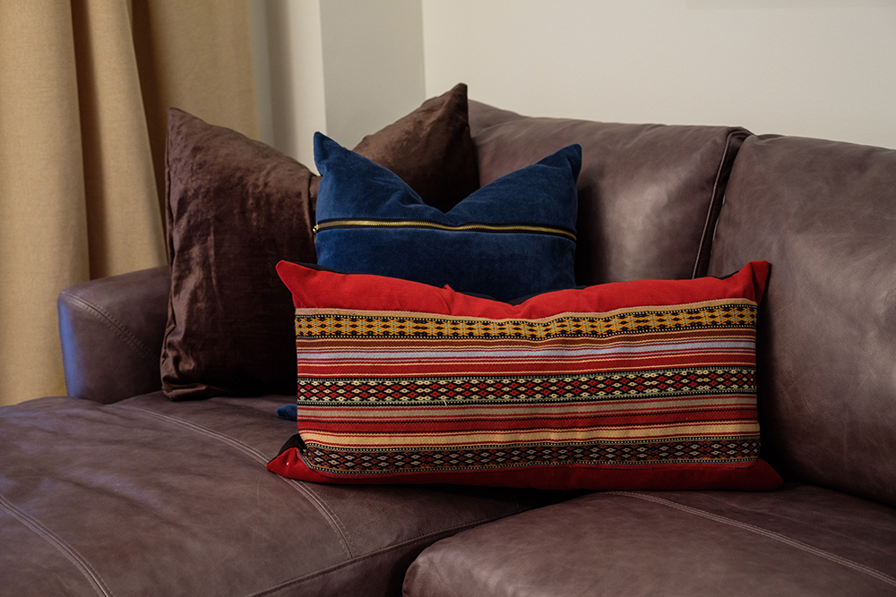 Brown leather couch with red and blue throw pillows