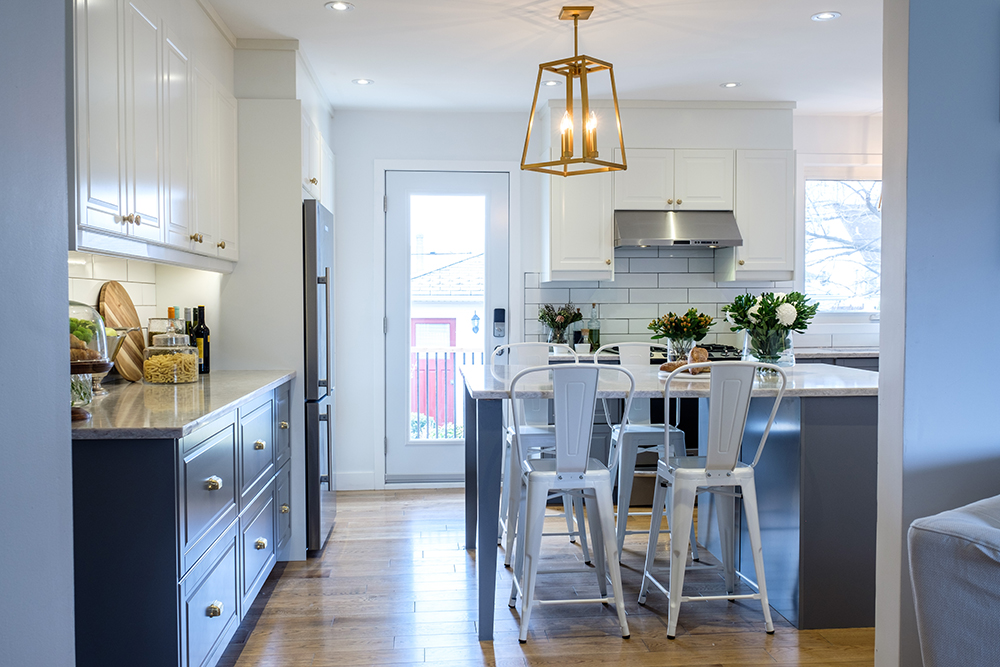 Looking through to a large white modern kitchen with a gold pendant light