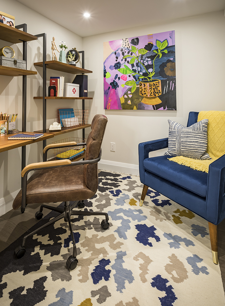 Cozy home office with a brown leather desk chair, industrial shelving and mid century modern blue armchair