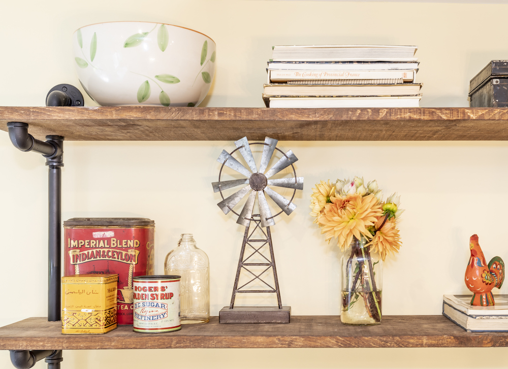 Industrial pipe and pine shelving holds collectibles and cookbooks in a newly renovated kitchen