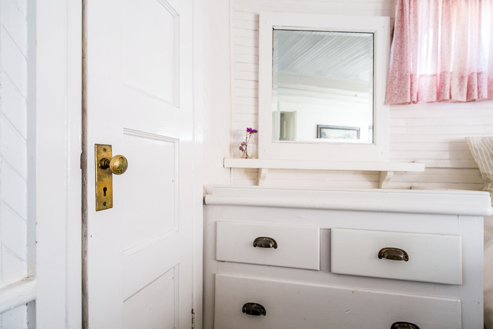 White bathroom with stylish vintage dresser cabinet.