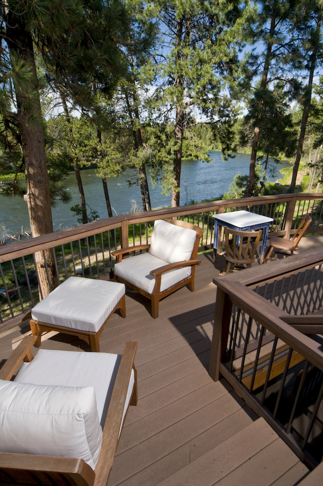 brown deck with white furniture in front of blue lake