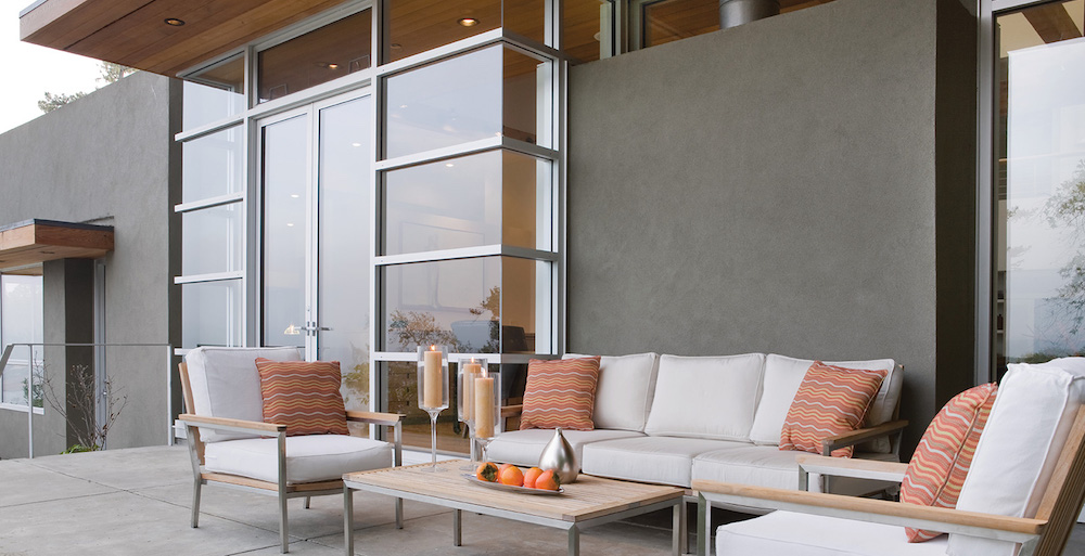 modern grey patio with white outdoor furniture and orange cushions