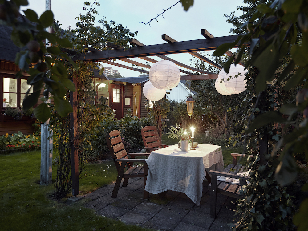 wooden pergola with white hanging lights over outdoor dining table