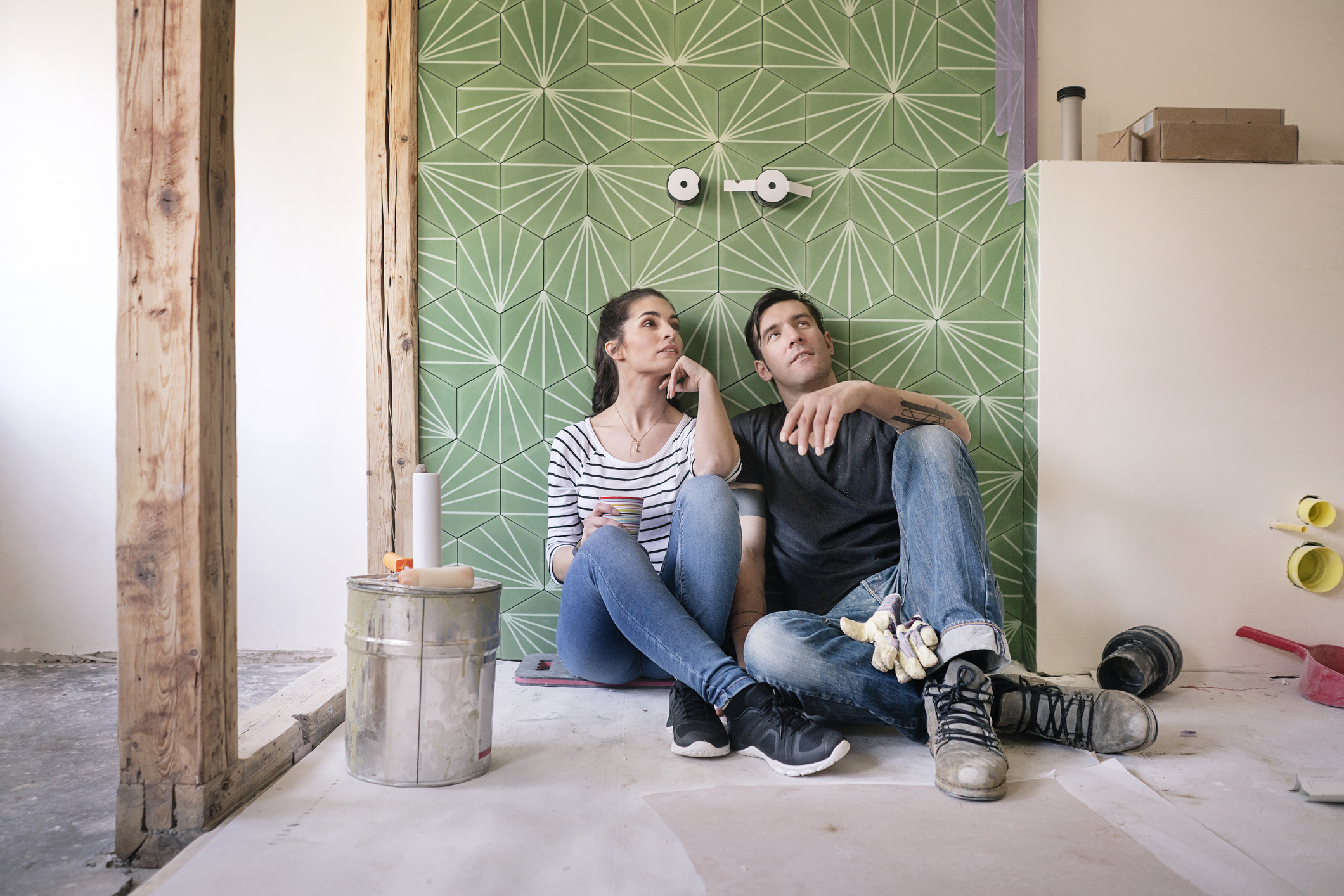 Couple renovating new house, sitting on ground planning bathroom.