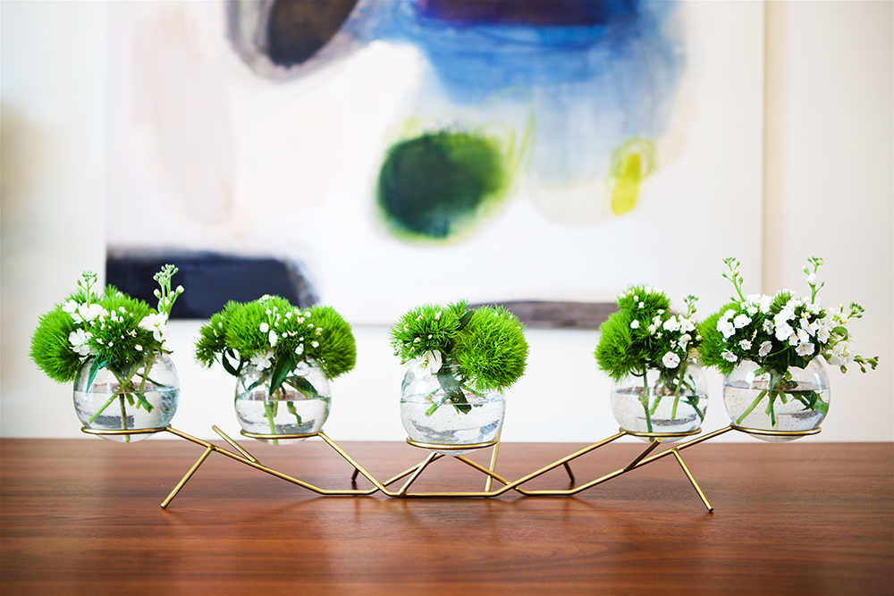Fresh green flowers stands out against the polished teak wood of the mid-century-modern dining table