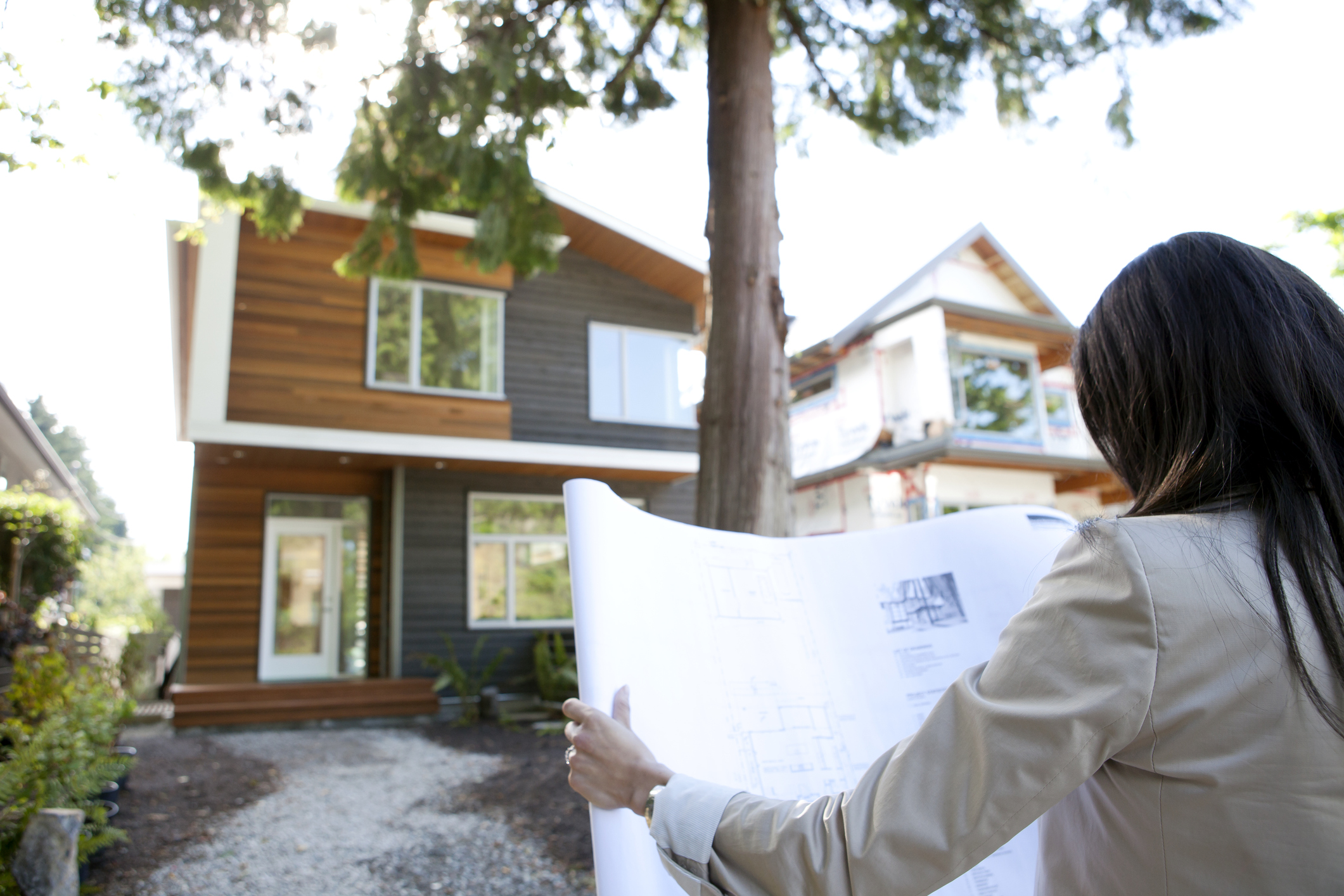 woman standing outside of house with blueprints