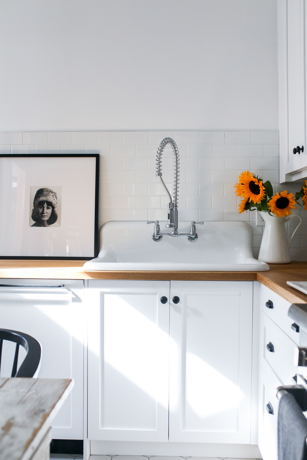 Farmhouse-style sink with modern chrome faucet and black knobs
