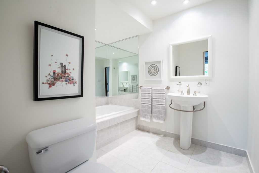 White bathroom with standing sink and pot lights