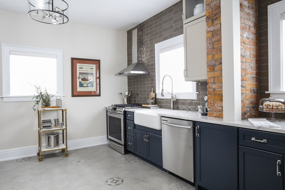 Renovated kitchen with modern blue cabinets and exposed brick.