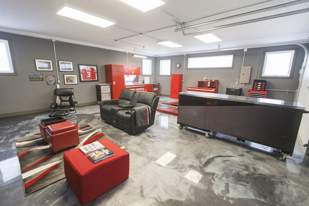 A modern garage with black leather chairs, red stools and car tools