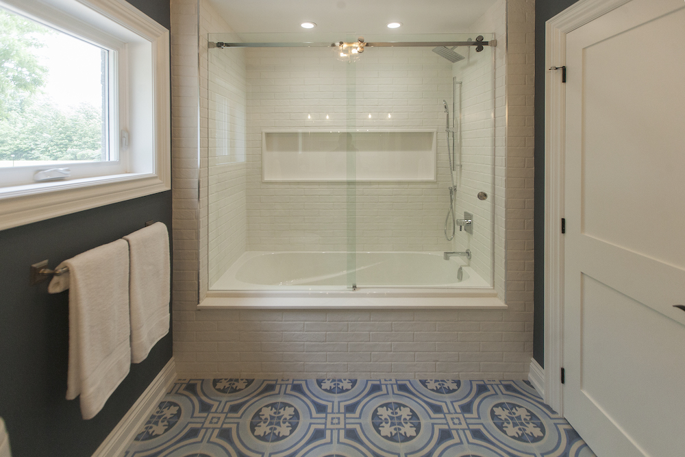 Modern bathroom with blue patterned tile floors and white subway tiled shower bath combo