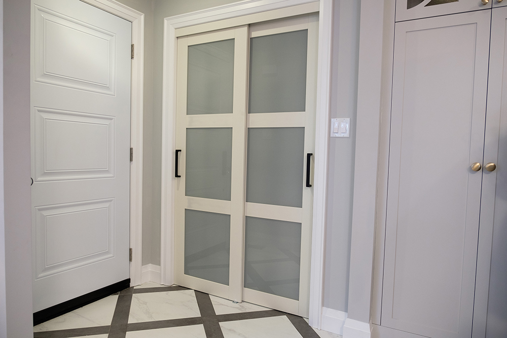 Front hall entry with a coat closet with sliding door handles and woven tile pattern on the flor