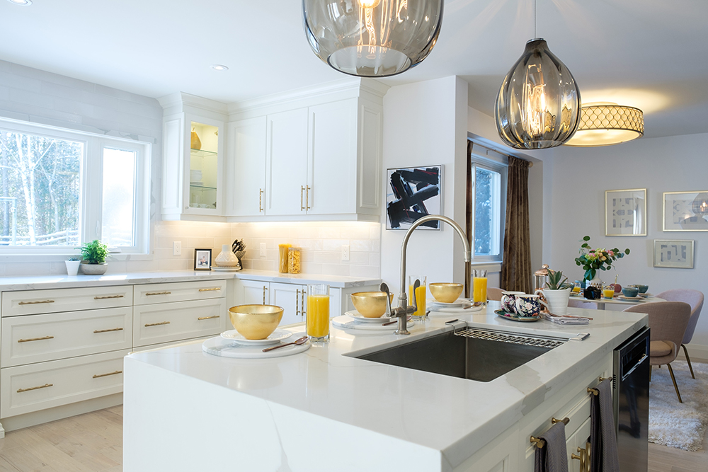 Chic modern kitchen with a centre island, large pendant lights and white cabinets with gold hardwar