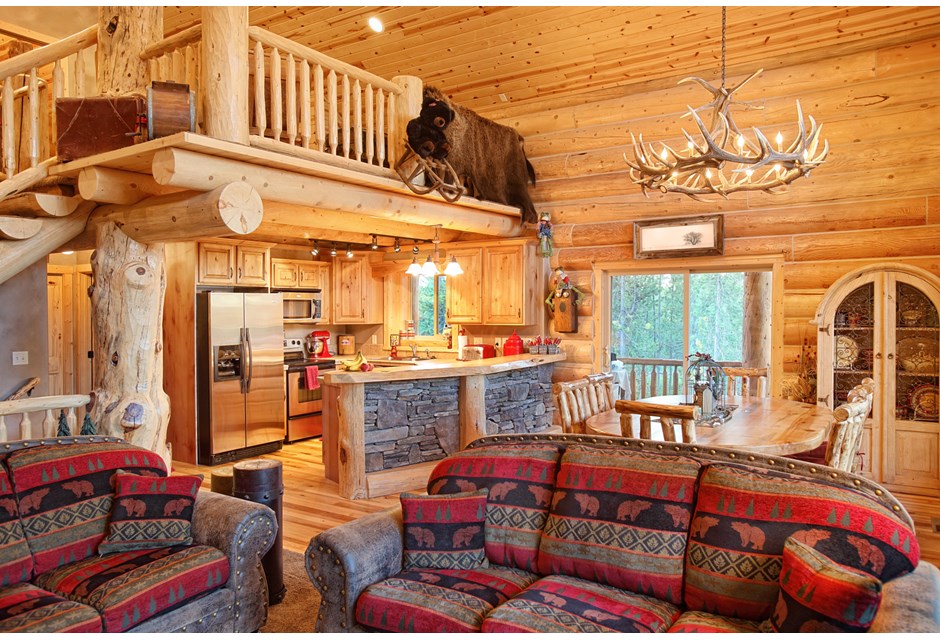 A wood cabin with animal decor, patterned couches and plenty of wood and stone