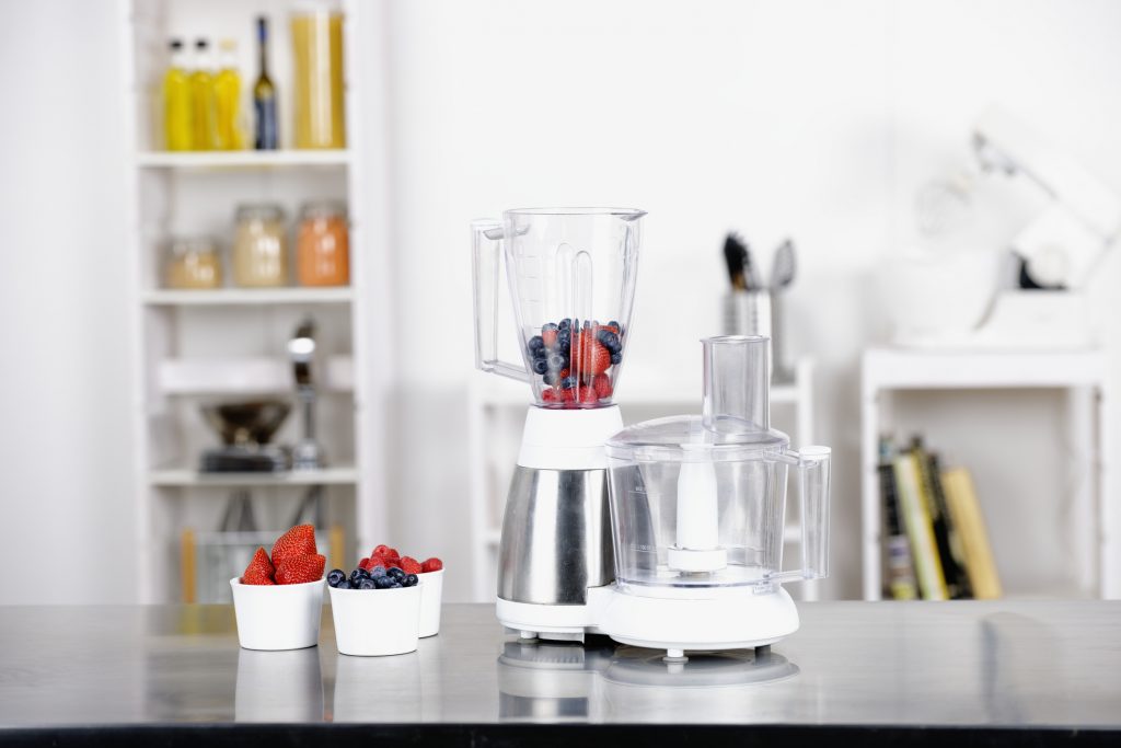 Blender with cups of fruit next to it