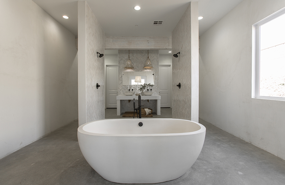 A minimalist bathroom renovation with a freestanding tub and unique light fixtures