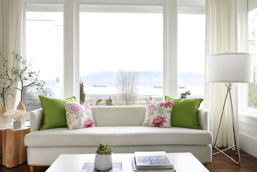white soda in front of picture window with two green cushions and two pink floral cushions