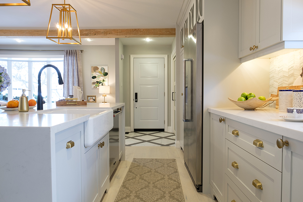 Modern kitchen island with a white apron sink and white cabinets with gold hardware