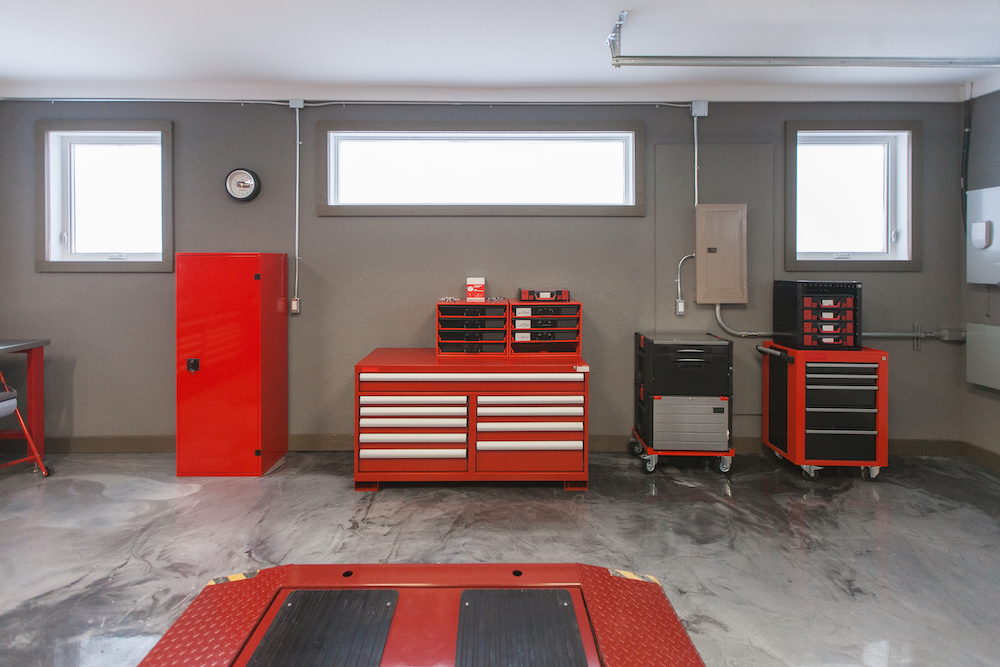 Red car tool cabinets sit against a grey wall with window