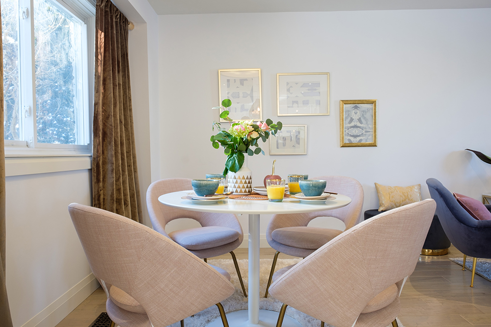 Modern breakfast nook with pink upholstered egg chairs, a shearling carpet and framed artwork on the wall behind