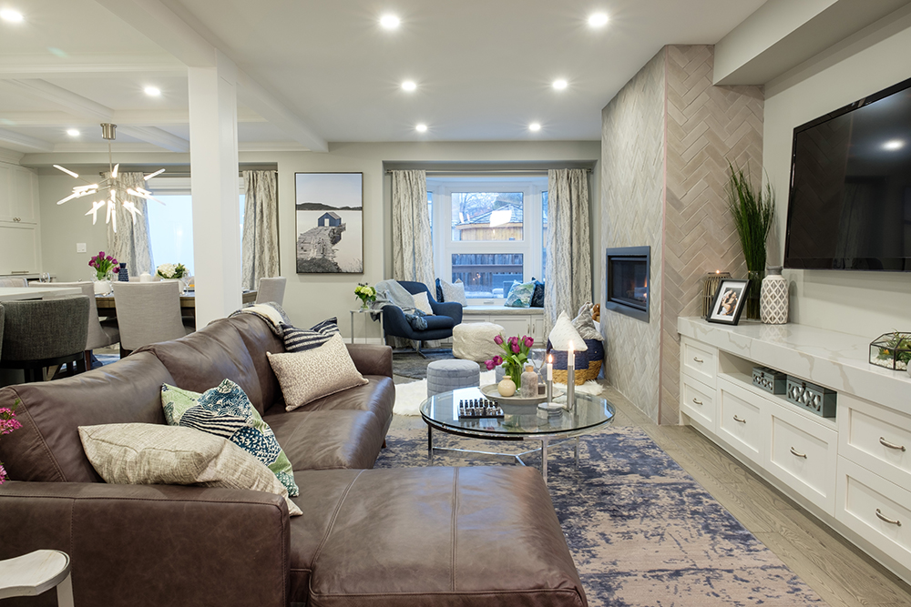 A comfortable modern living area features a large TV and brown leather sectional