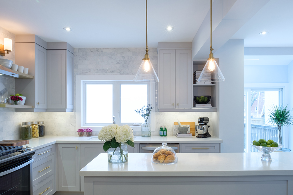 A chic white kitchen with large centre island and two glass pendant lamps