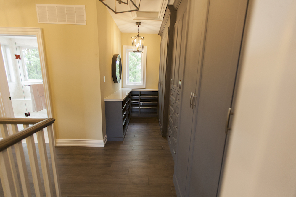 Hallway with a wall of grey built in closets, drawers and shoe racks