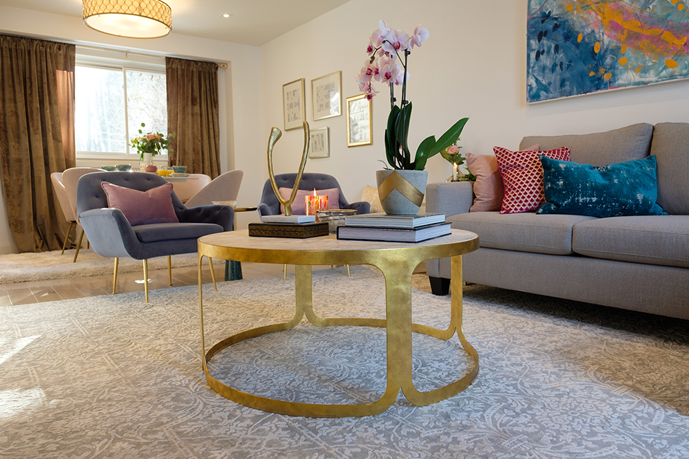Modern living room with a gold coffee table topped with books and an orchid, a grey couch and artwork on the walls